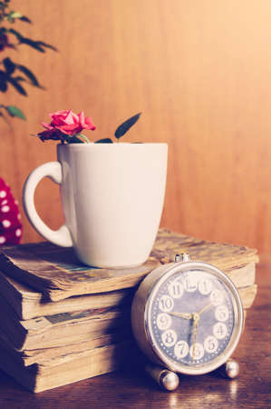 Cup, books and flowers on wooden background. Romantic setting in natural light