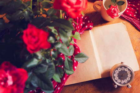 Open old book and roses on wooden background and scarf with polka dots.の写真素材