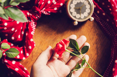Hand holding beautiful pink rose on wooden retro background.の写真素材