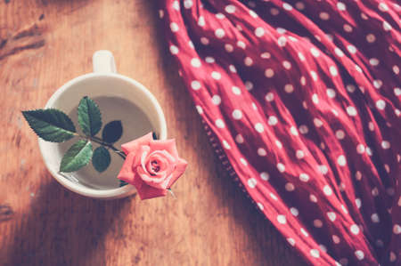 Beautiful pink rose in a cup on a wooden retro table.の写真素材
