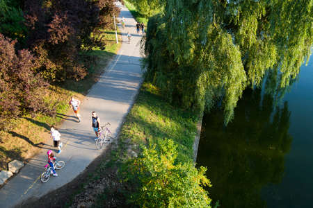 Bucharest, ROMANIA - June 22, 2015: People riding their bycicles or jogging at sunset in Tineretului park, Bucharest. BUCHAREST -June 22, 2015のeditorial素材