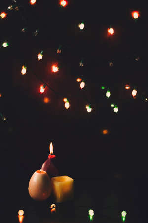 Three colorful candles on a dark background with Christmas lights. Filtered and faded efeect.の写真素材