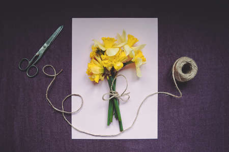 Daffodils, thread and scissors on the table. Florist workplace, still life top viewの写真素材