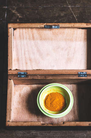 Turmeric powder on a green plate in a wooden box.