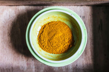 Turmeric powder on a green plate in a wooden box. Closeup
