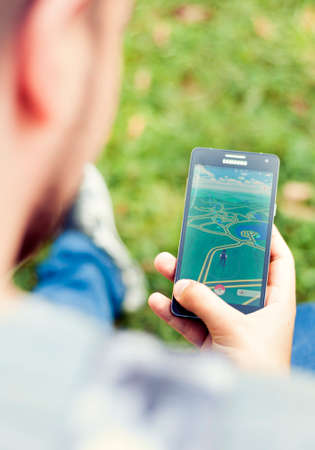 Bucharest, ROMANIA - August 20 2016: Young man playing Pokemon Go on his mobile phone in the park....