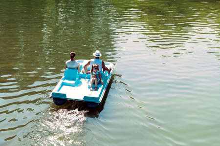 Bucharest, ROMANIA - August 21 2016: Chic young lady and her parents on a boat on a Sunday afternoon. Family relaxing in the park. BUCHAREST -August 21 2016のeditorial素材