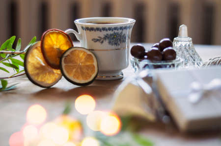 Preparing gifts for Christmas. Wooden table full of bags, boxes, cups and various objects. Focus on...