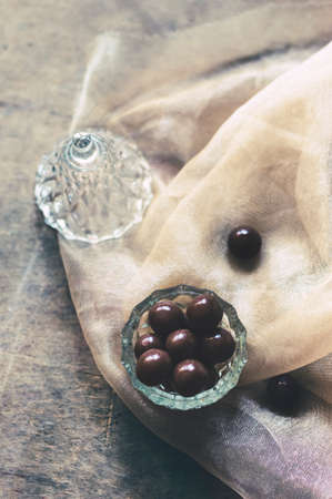 Chocolate dragee in a lovely glass bowl on wooden background.の写真素材