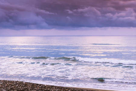 Calm sea waves against a dark and stormy sky. Rich ultraviolet tones