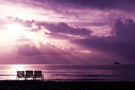 Seascape with heavenly light rays and three chairs on the beach in Larnacaの写真素材