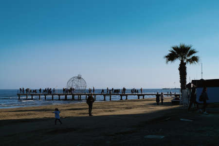 People strolling along Finikoudes beach in Larnaca on a sunny day in January.のeditorial素材