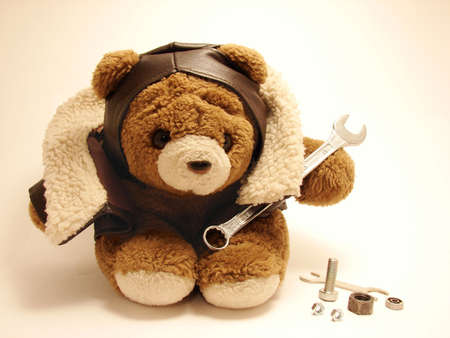 teddy bear dressed as a pilot holding  a spanner ina white ocher background.                               の写真素材
