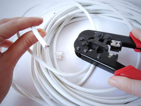  Hands using network cable (cat5e) crimper & the bunch of a stranded patch cable on white background                             の写真素材