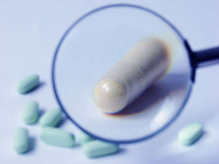  the pill close up with a magnifier and some otheres are around.                              の写真素材