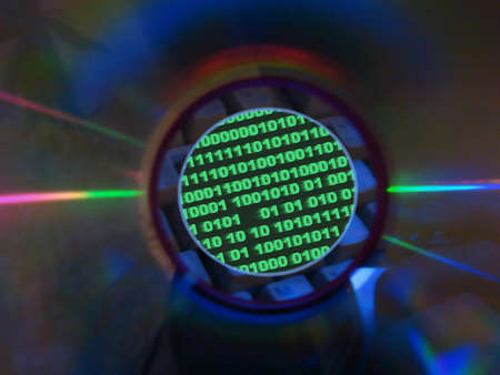   keyboard & binary code visible through compact disk hole                             の写真素材