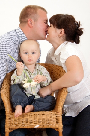 Mother and father are kissing while their baby is playing with a flower  の写真素材