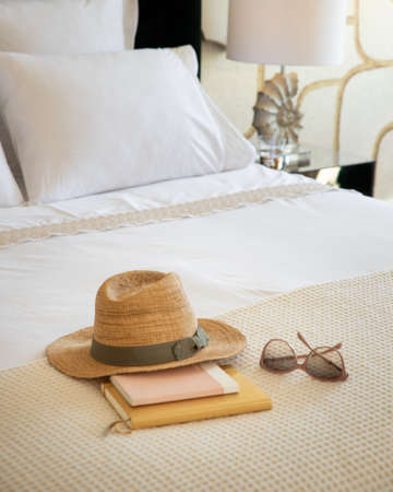 Detail of a bed with books hat and sun glassesの写真素材