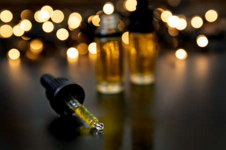CBD oil drops over moody dark background with dim lightingの写真素材
