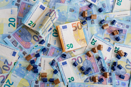 House model on background of European twenty and fifty euro bills banknotes surrounded by coins. Property concept, house mortgage, home loan, real estate investment.の写真素材