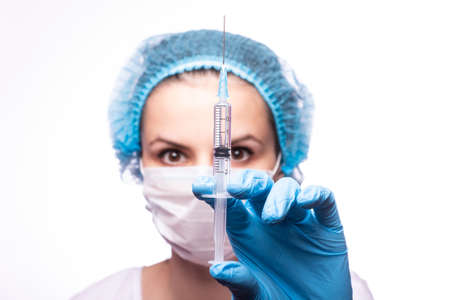 beautiful young girl in medical mask wearing glasses and gloves is holding a syringeの写真素材