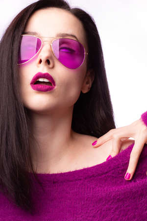 girl in a purple sweater, purple glasses with purple lipstick on her lipsの写真素材