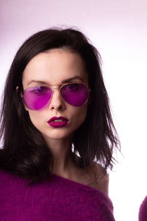 girl in a purple sweater, purple glasses with purple lipstick on her lipsの写真素材