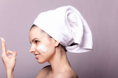 woman with cream on her face, mask on the face, a towel on her head, skin problem conceptの写真素材