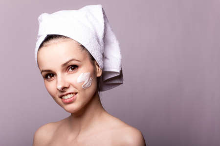 woman with cream on her face, mask on the face, a towel on her head, skin problem conceptの写真素材