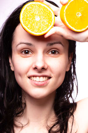 beautiful young girl with an orange in her hands, vitamins, summer, wet hair