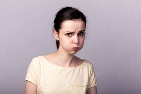 girl in a yellow T-shirt, brunette, clean skin, gray background