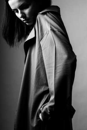 beautiful young girl in a trench vertical photoの写真素材