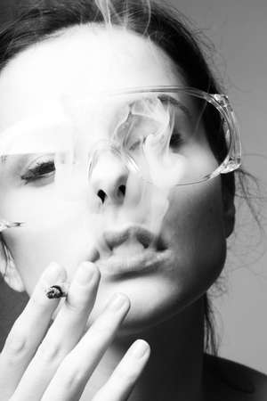woman in protective glasses smokes a cigaretteの写真素材