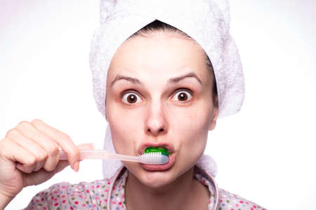 beautiful girl brushes her teeth in a towel on her head, close-up portraitの写真素材