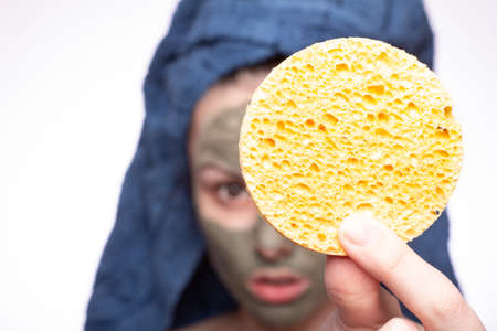 young woman in a towel on her head after shower with a sponge in hands
