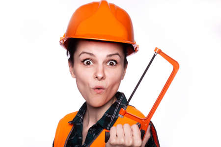 cute woman builder in a protective helmet and an orange vest with a tool in his hands, a hardware storeの写真素材