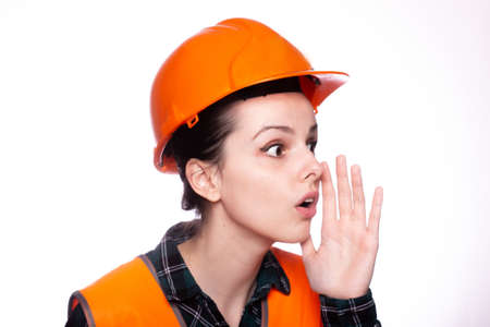 builder woman in orange helmet, light backgroundの写真素材