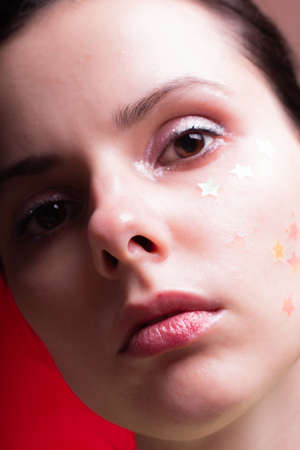 woman with sparkles on her face, close-up portraitの写真素材