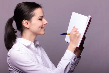 student girl in a white shirt holds a pink notebookの写真素材