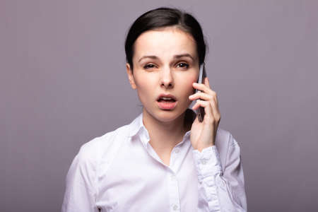 beautiful woman manager is talking on the phone, office style, call center, gray studio backgroundの写真素材