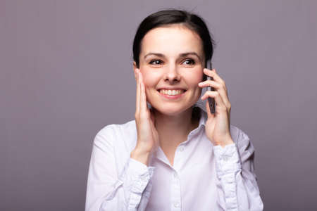 girl in a white shirt communicates on the phoneの写真素材