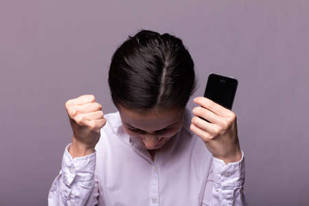 panicking woman in a white shirt speaks on the phone, call center operator, gray studio backgroundの写真素材