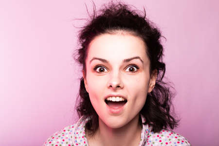 beautiful curly girl in pajamas, pink background