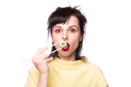 Woman eating sushi and rolls on a light backgroundの写真素材
