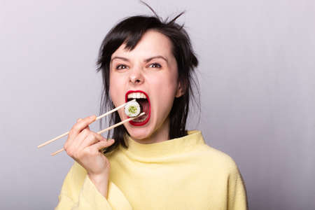 woman in a yellow sweater eating sushi