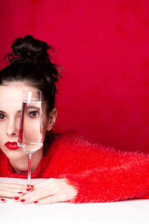 woman in red looks through a glass of water, artの写真素材