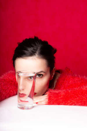woman in red looks through a vessel with waterの写真素材
