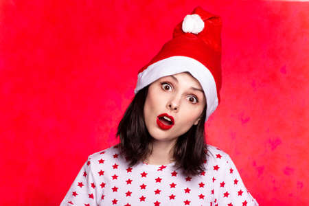 beautiful woman in a t-shirt with a star and a santa claus hat, with red lipstick on her lipsの写真素材