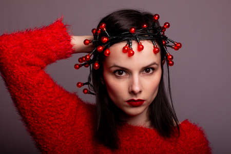 beautiful girl in a red sweater with a garland on her headの写真素材