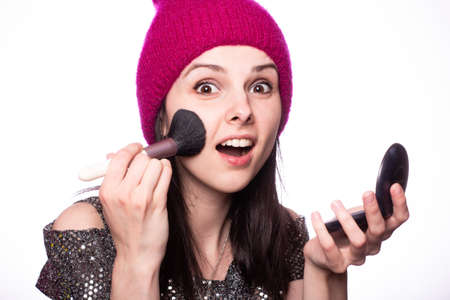 beautiful woman make-up artist does makeup with a brush, light studio backgroundの写真素材